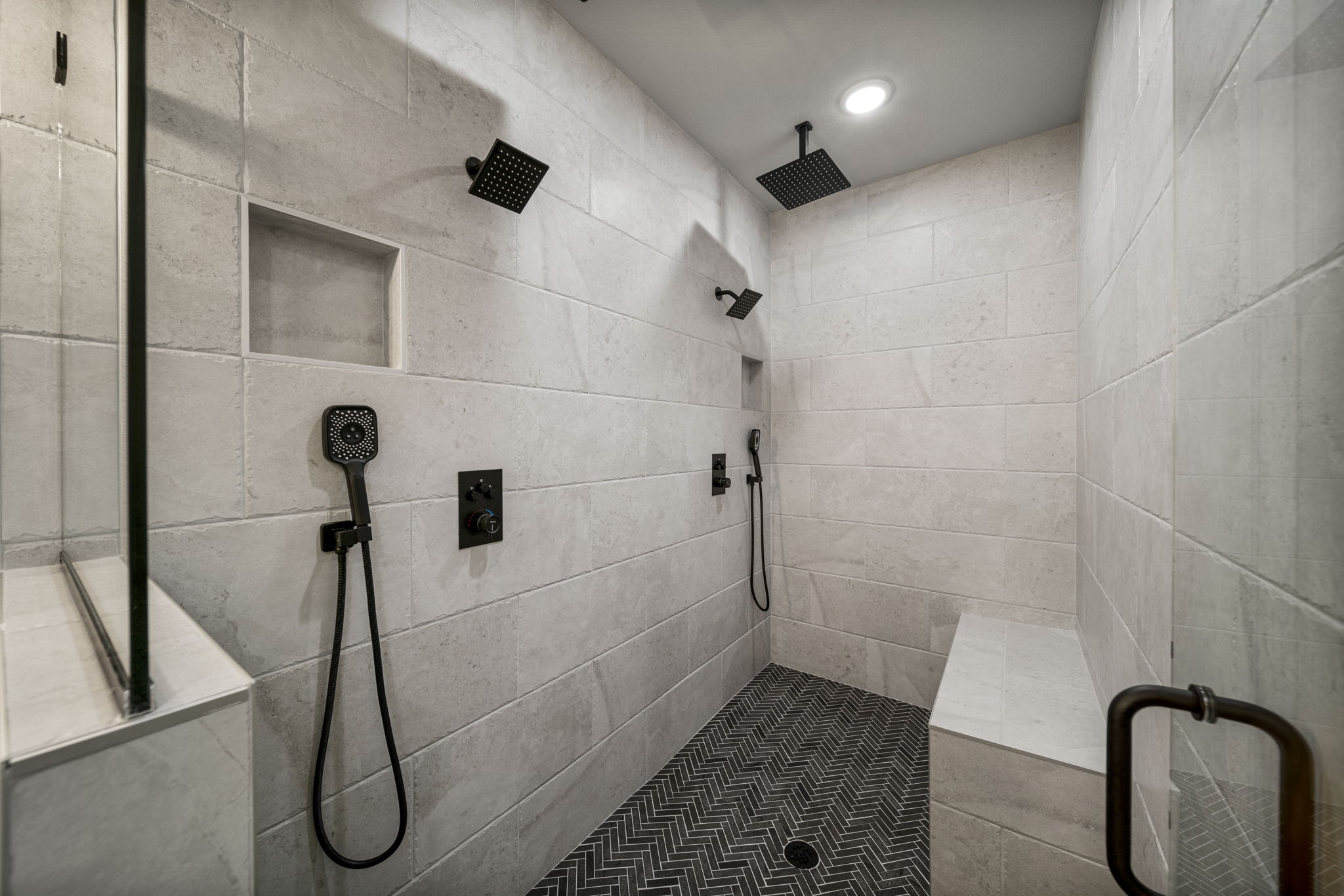 Modern bathroom with designer tiles, sleek cabinetry, and a large glass shower by Mahogany Homes.